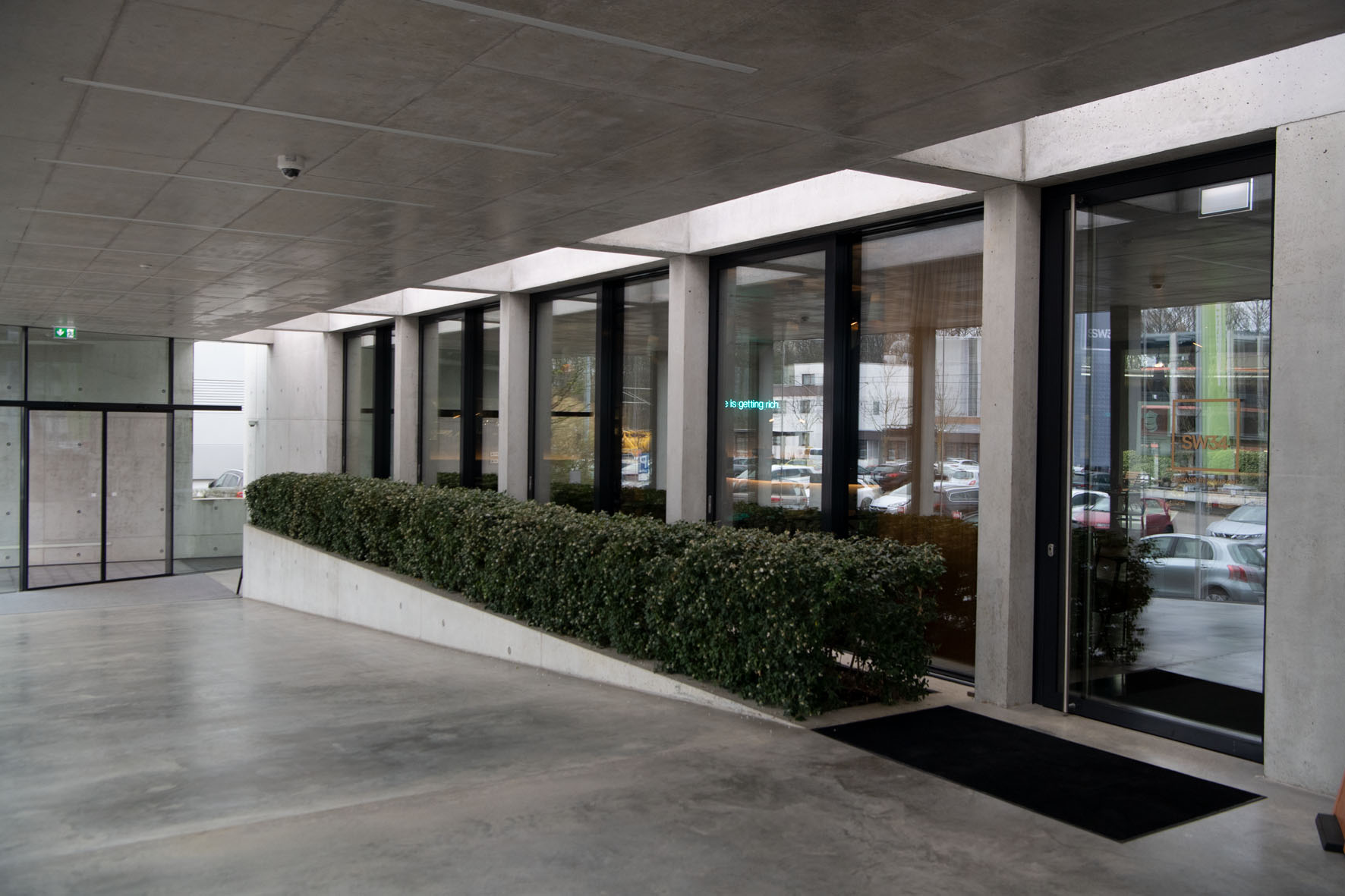 SW34 Entrance: Eingangsbereich mit Betonarchitektur, Glasfront und SW34-Schriftzug, Schelmenwasenstraße 34